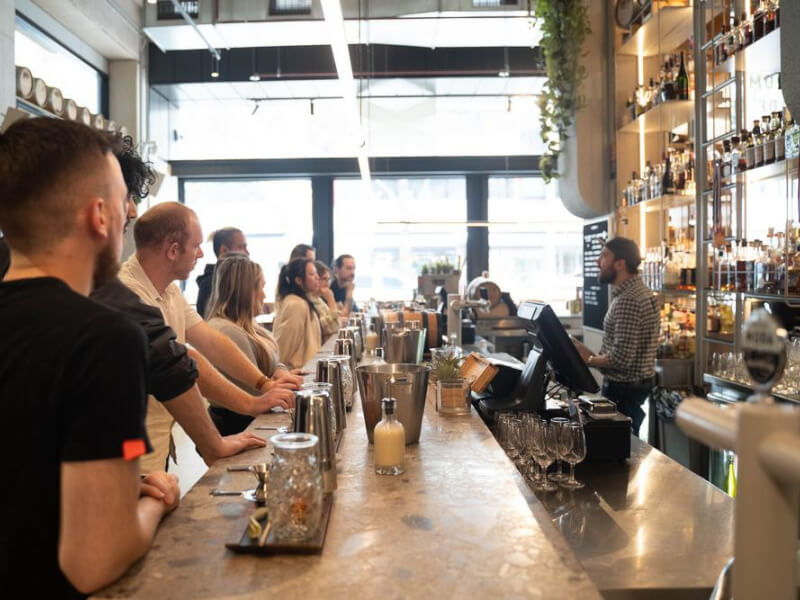 A team of people standing at a bar with cocktail making equipment in front of them